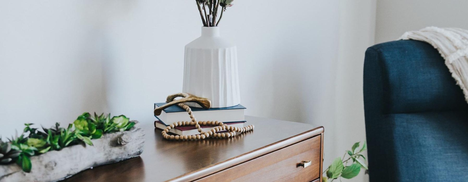 a dresser with a vase of plants on top